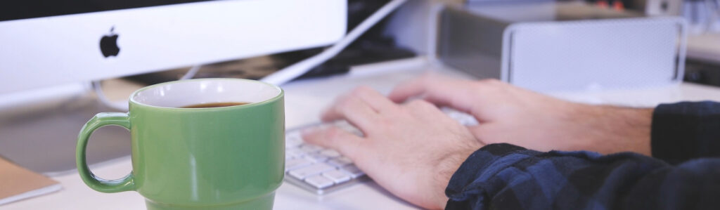 Green mug with hands on keyboard
